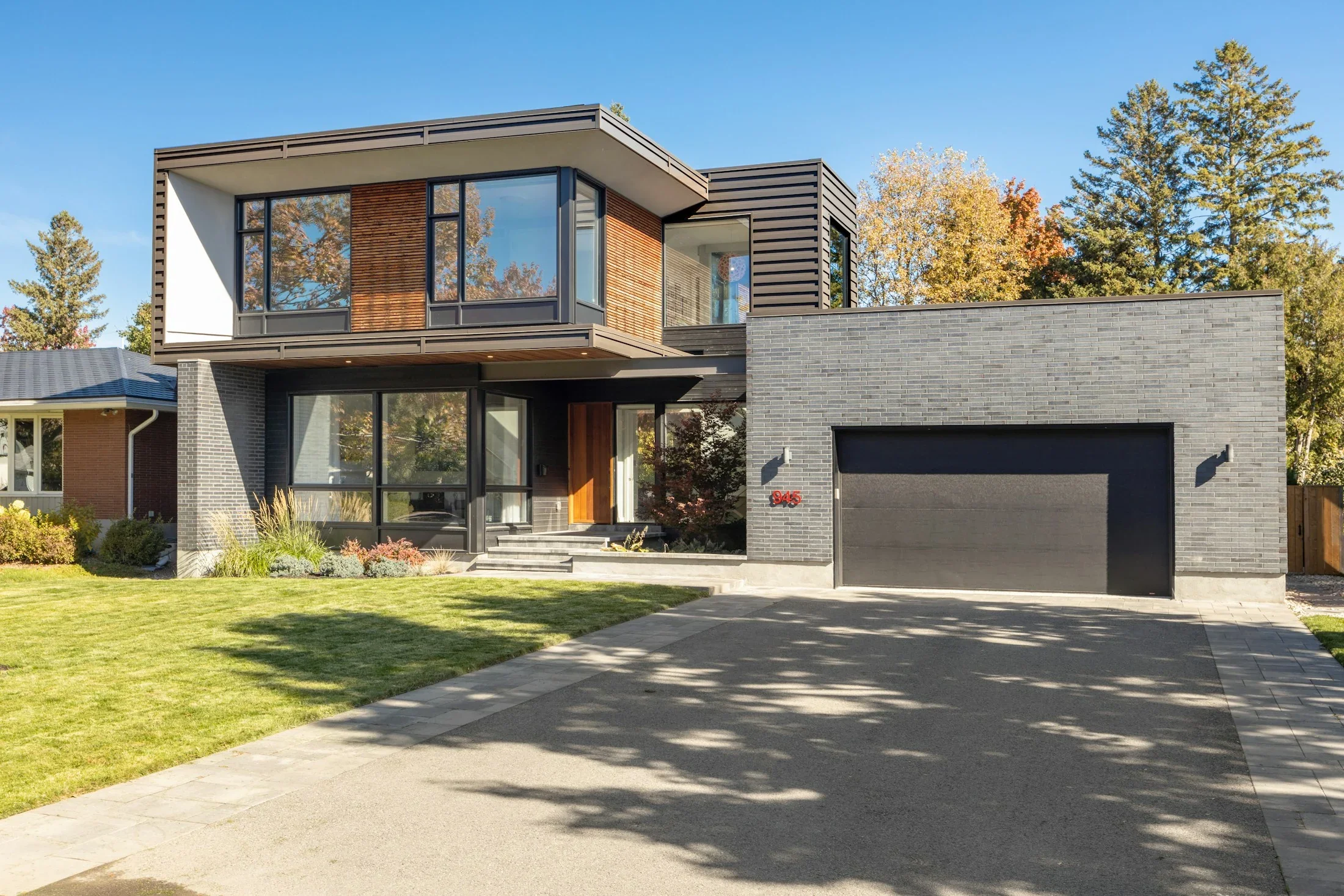 A modern brick and timber home with a garage and landscaped front yard