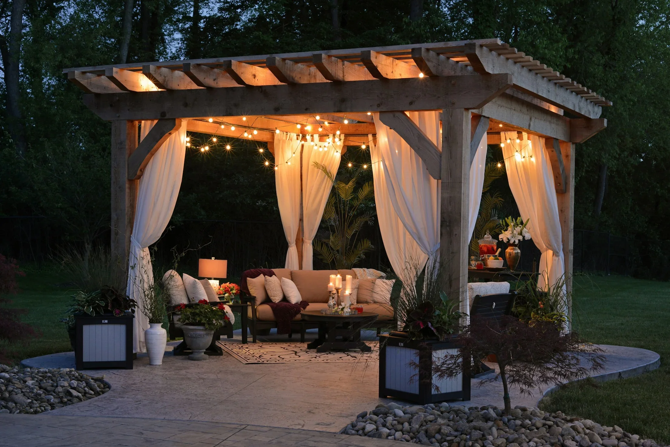 A garden pergola with comfortable seating and warm string lights