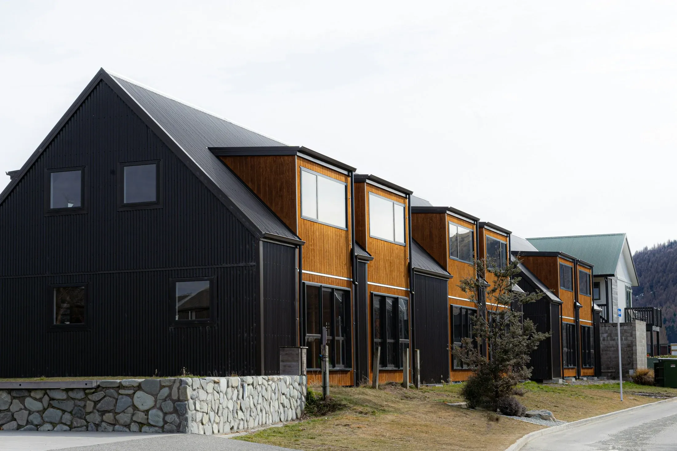 A row of contemporary homes with stone walls and timber cladding